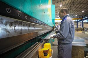 Lavoratore alle prese con una macchina utilizzata per la piegature lamiere all'interno della azienda Albertini srl locata a Vobarno.